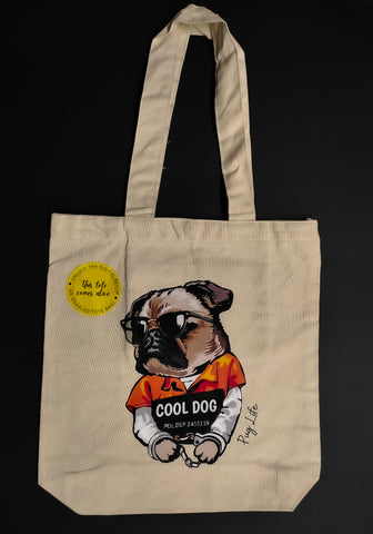 A tote with an image of a Pug in jail clothes with handcuffs, holding a placard and wearing sunglasses. On the side the words - 'Pug life' is written.